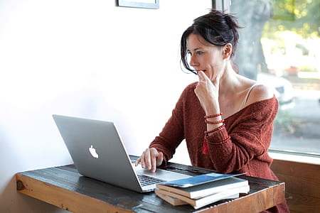 woman touching chin while scrolling through the laptop thumbnail