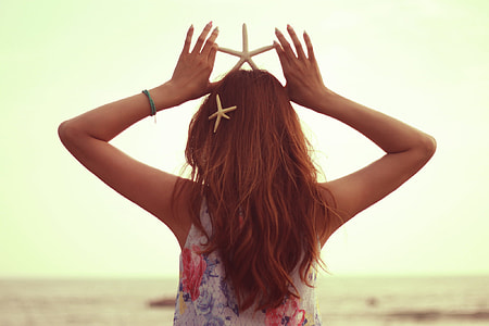 selective focus photography of woman holding white star fish on head thumbnail