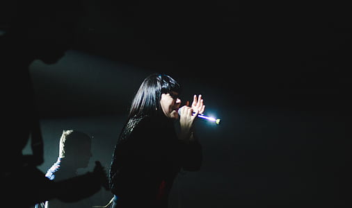 woman singing with microphone in dark room thumbnail