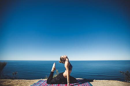 woman wearing black doing yoga beside sea under blue sky thumbnail