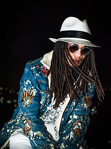 man wearing white and black fedora hat and bleu denim jacket inside room in bokeh photography thumbnail