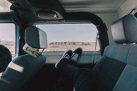 person in black jeans laying inside car thumbnail