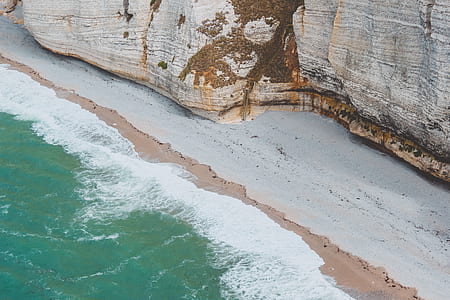 aerial photo of gray seashore near gray cliff during daytime thumbnail