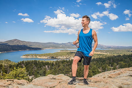 man standing on hill with body of water in the background thumbnail
