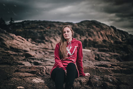 woman in red pullover hoodie sitting on rock thumbnail