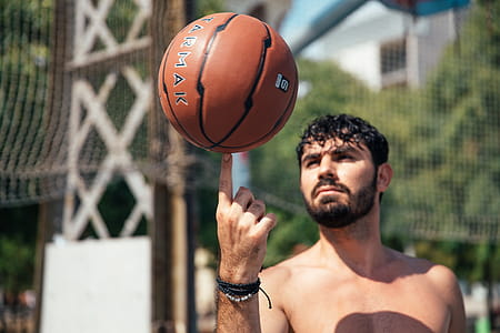 A young man spinning basketball on his finger in sunlight thumbnail