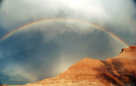rainbow arc over brown mountain thumbnail