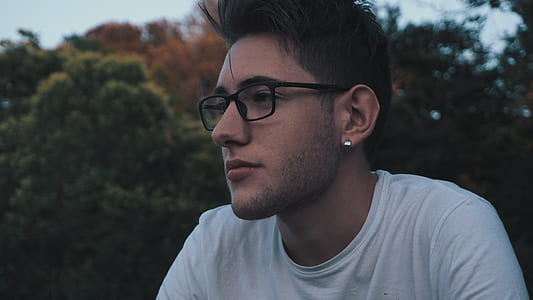 man in white crew-neck shirt near green trees during daytime thumbnail