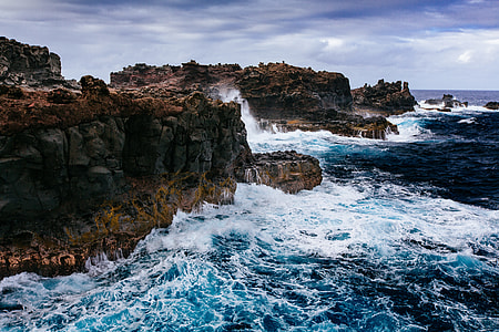 photo of blue and white body of water near rocks thumbnail