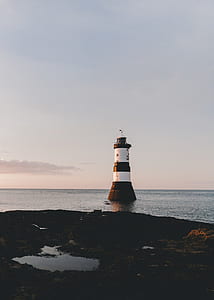 white and black lighthouse in body of water during daytime thumbnail