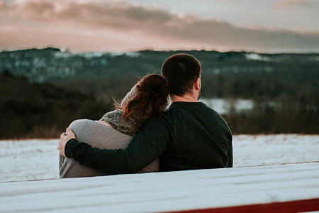 man holding woman while sitting on bench thumbnail