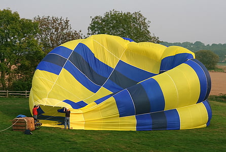 blue and yellow hot air balloon near trees thumbnail