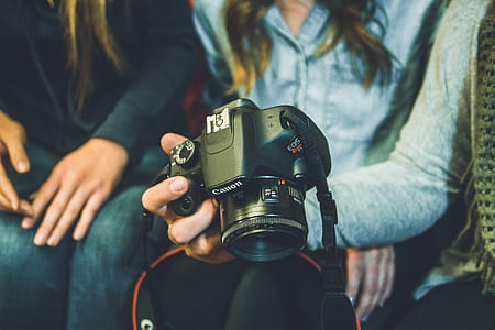 shallow focus photography of person holding black Canon DSLR camera thumbnail