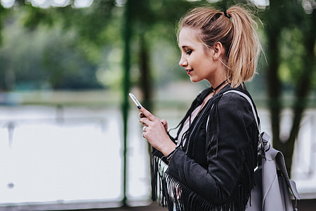 Blonde woman in a black jacket and ripped jeans by a green handrail thumbnail