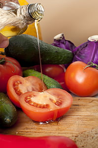 person pouring liquid on sliced tomatoes placed on brown wooden surface thumbnail