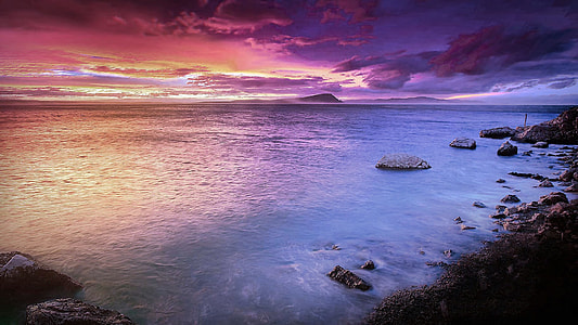 body of water near seashore during purple and orange sky thumbnail