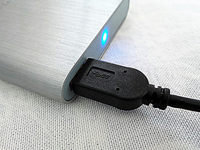 turned-on silver power bank with black USB cablke thumbnail