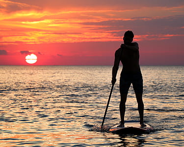 Silhouette photography of man holding pole during sunset thumbnail