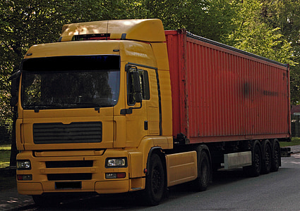 yellow and red container truck packed under trees thumbnail