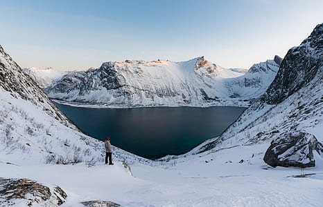 person standing near mountain peak and body of water thumbnail