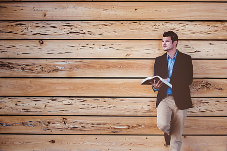 man in brown suit jacket leaning on brown wall thumbnail