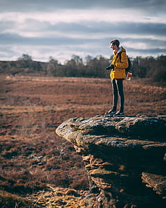 man standing on gray rock near green leafed trees thumbnail