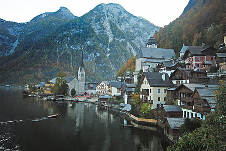 brown and gray houses beside lake and mountains thumbnail
