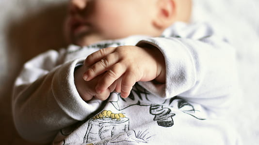 sleeping baby wearing white jacket thumbnail