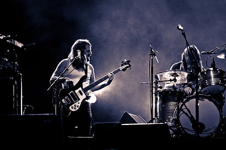 closeup photography bass guitarist playing beside drummer on stage thumbnail