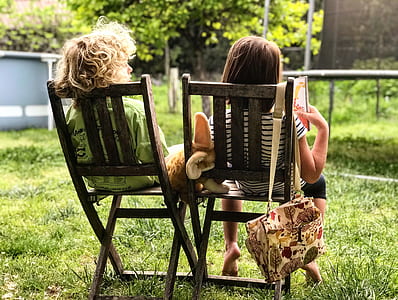 two children sitting on black wooden chairs thumbnail
