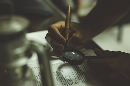person using magnifying glass on book thumbnail
