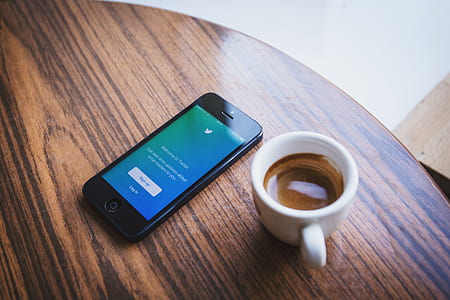 black iPhone 5 beside cup on tabletop thumbnail