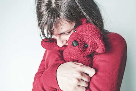 person wearing red sweat shirt and hugging bear plush toy thumbnail