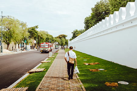 man wearing white top and black bottoms walking on pathway thumbnail