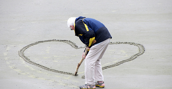 person drawing heart on gray sand thumbnail