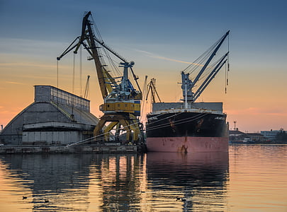 two yellow and gray heavy equipments on calm water during golden hour thumbnail