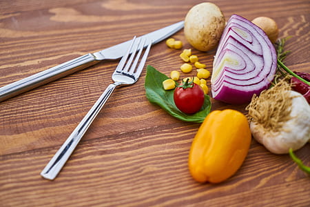 silver metal knife and fork beside vegetables on brown wooden surface thumbnail
