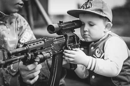 boy wearing flat brim cap holding assault rifle thumbnail
