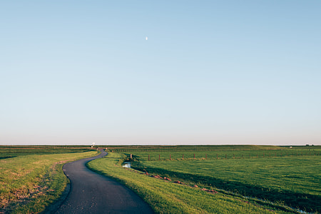 black asphalt road along green grass field under blue sky at daytime thumbnail