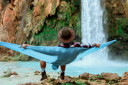 woman sitting on teal hammock near waterfalls during daytime thumbnail