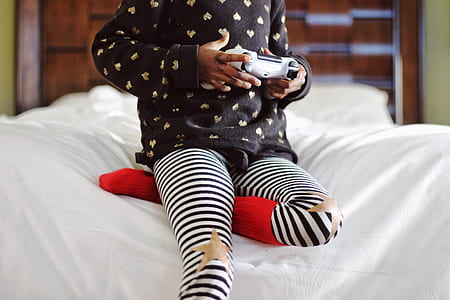 toddler holding PS4 controller sitting on bed thumbnail