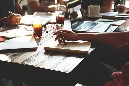 person sitting in front of table holding pen on top of opened book thumbnail