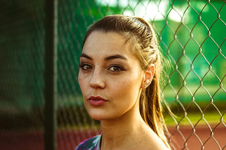 woman leaning on gray chain link fence thumbnail