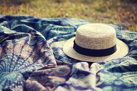 brown and black straw hat on blue floral textile thumbnail