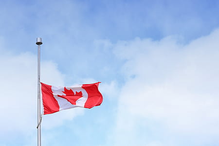 Canada flag rising on pole under white clouds during daytime thumbnail