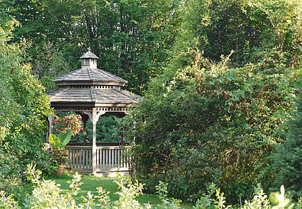 A small wooden gazebo in a backyard garden. thumbnail