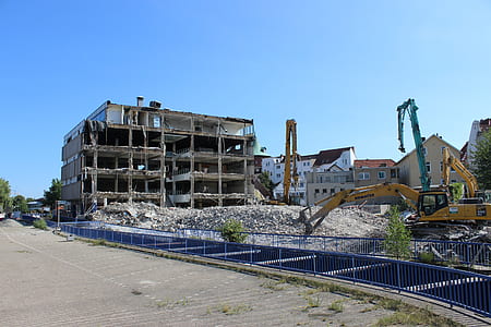 yellow excavator outside demolished building thumbnail