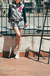 A young blonde woman in casual jacket standing against metal railing thumbnail