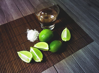 clear shot glass filled with liquid substance beside sliced lime thumbnail
