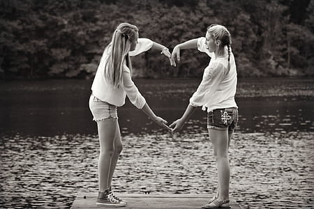 grayscale photo of two woman doing heart sign thumbnail